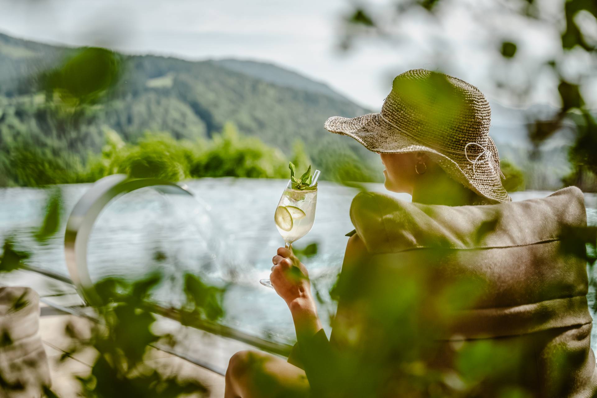 Frau trinkt Cocktail am Infinitypool des Hotels Bergkristall