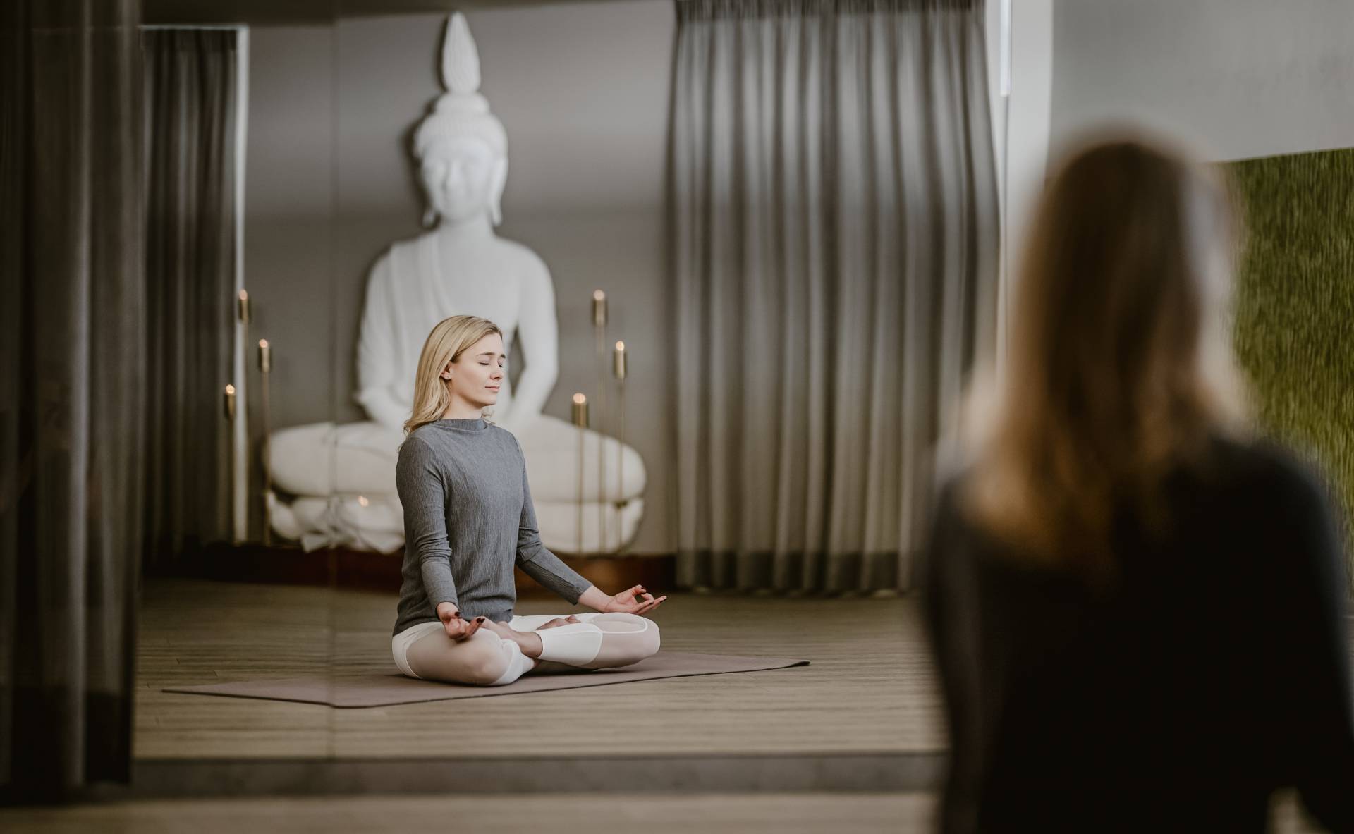 Frau meditiert bei Kerzenschein im Yogaraum
