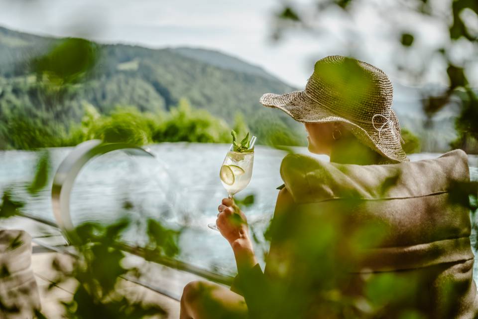 Frau trinkt Cocktail am Infinitypool des Hotels Bergkristall