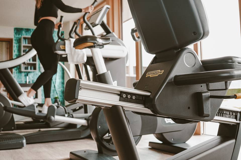 Frau auf Crosstrainer im Fitnessraum des Hotels Bergkristall im Allgäu