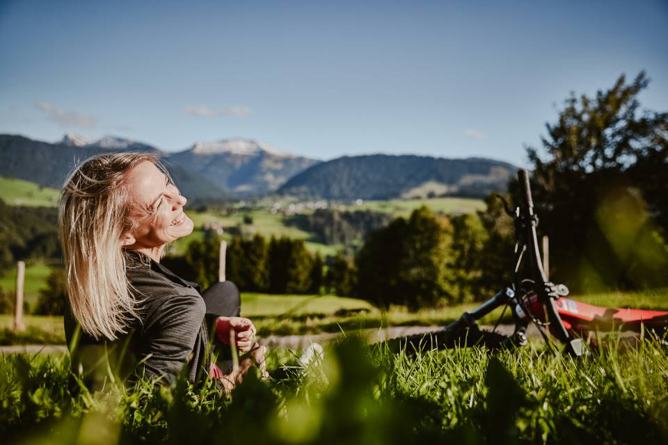 Frau lachend im Gras mit E-Bike