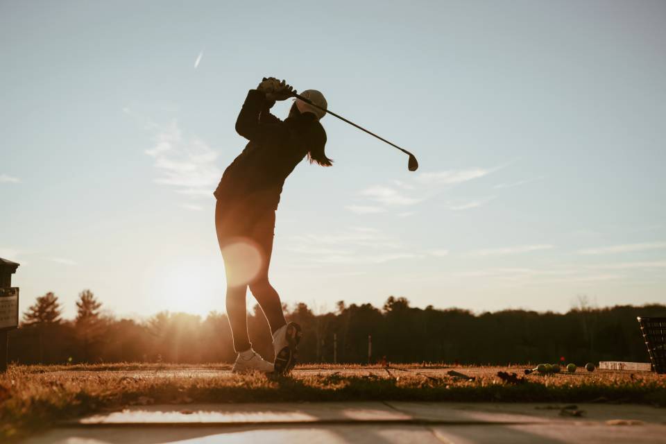 Frau spielt Golf bei Sonnenuntergang