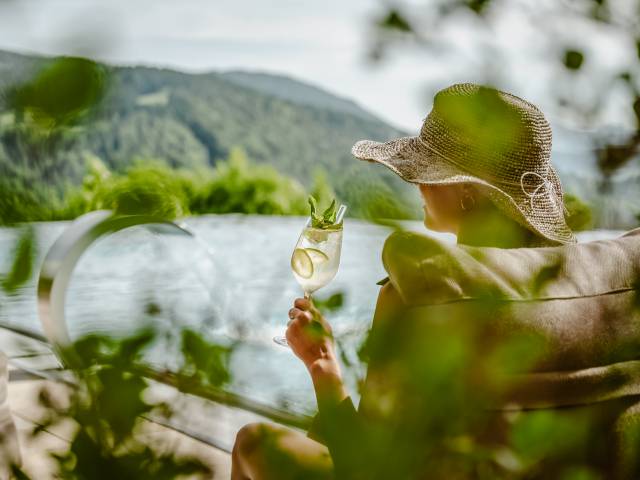 Frau trinkt Cocktail am Infinitypool des Hotels Bergkristall