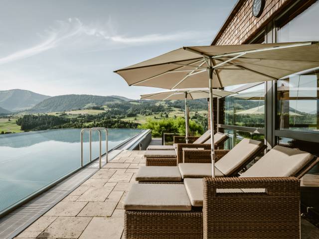 Außenansicht Infinitypool des Wellnesshotel Bergkristall im Allgäu mit Sonnenliegen