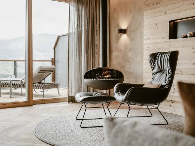 Sessel mit Kamin in Natursuite Gipfelstürmer im Hotel Bergkristall
