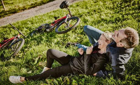 Paar lachend in Wiese mit E-Bikes