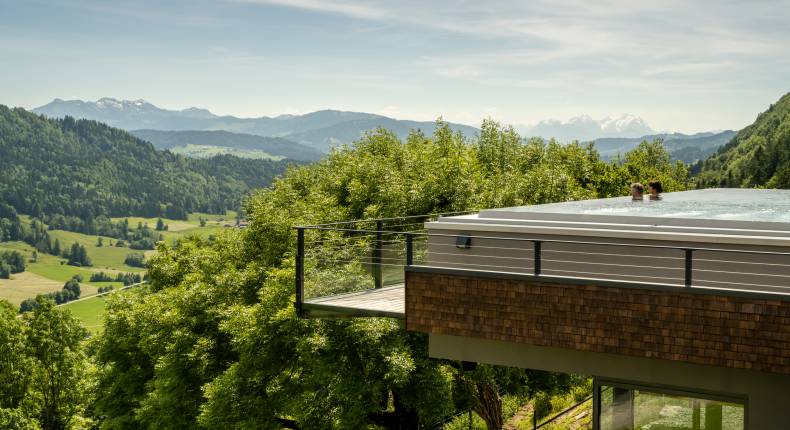 Paar im Pool mit Blick auf Allgäuer Berge