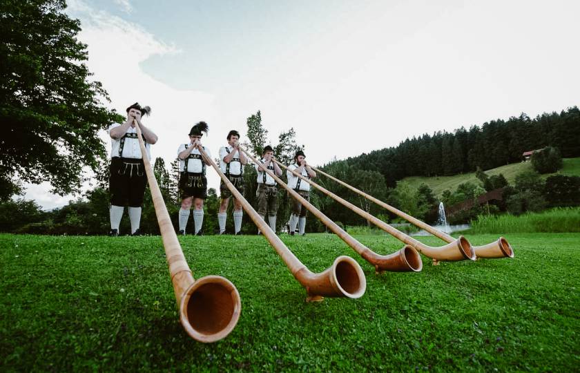 Männer in Trachten spielen Alphorn